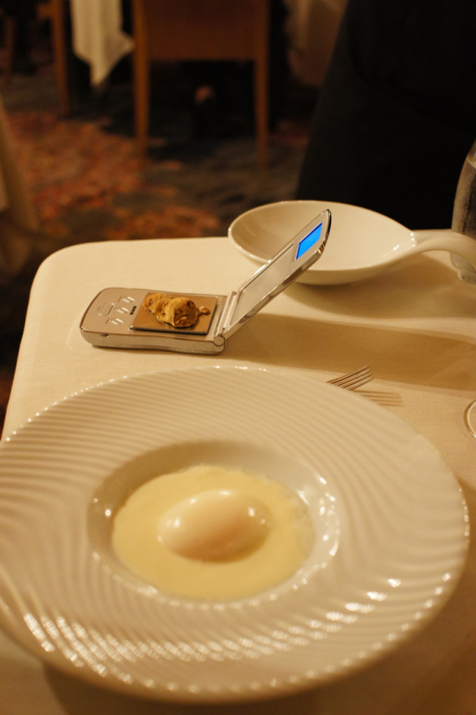 O primeiro prato é um ovo poché sobre um creme de queijo branco. Eles trazem o tartufo e o pesam antes e depois de fatiar sobre o teu prato.