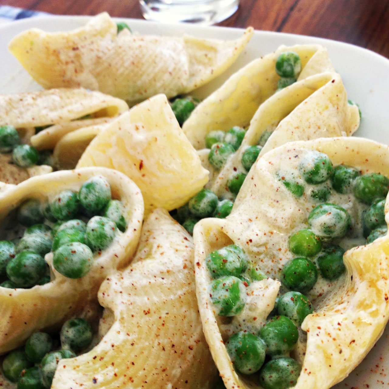 Lumaconi con piselli e panna – essa massa (que é “prima” do conchiglioni) faz as vezes de um barquinho que contém todo o recheio. (Foto: Simone Tortini)